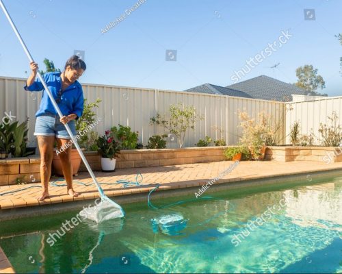 stock-photo-a-woman-in-shorts-and-a-blue-shirt-cleans-a-backyard-swimming-pool-with-a-net-under-clear-skies-2627862839